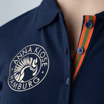 Close-up of the logo printed in gold on a blue long-sleeved polo shirt by Anna Klose Hamburg