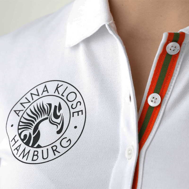 Close-up of the logo printed in black on a white long-sleeved polo shirt by Anna Klose Hamburg